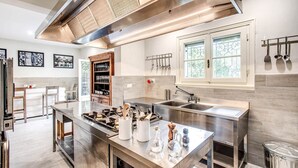 Een moderne keuken met roestvrijstalen apparatuur, een centraal kookeiland en een raam met uitzicht op groen.