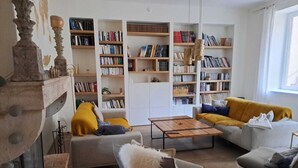 A living room with a fireplace, a sofa, a coffee table, and a bookshelf filled with books. - Beaujolais house with charm, pool, fireplace (Gleizé)