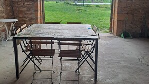 A rustic stone archway leading to a grassy outdoor area with a table and benches inside. - Beaujolais house with charm, pool, fireplace (Gleizé)