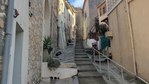 Eine enge Straße mit Steinbauten, einer Treppe und einem strahlend blauen Himmel.