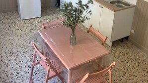 Eine kompakte Küche mit Kühlschrank, Mikrowelle, Spüle und einem kleinen Esstisch mit Stühlen.