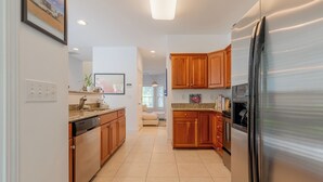 A modern kitchen with wooden cabinets, a stainless steel refrigerator, and a dishwasher.