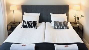 A double bed with white bedding, two black pillows with a bear pattern, and two black side tables with lamps.