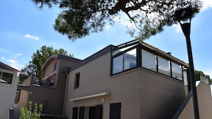 Un immeuble résidentiel moderne à deux étages, doté d’un toit plat, de grandes fenêtres et d’un balcon.