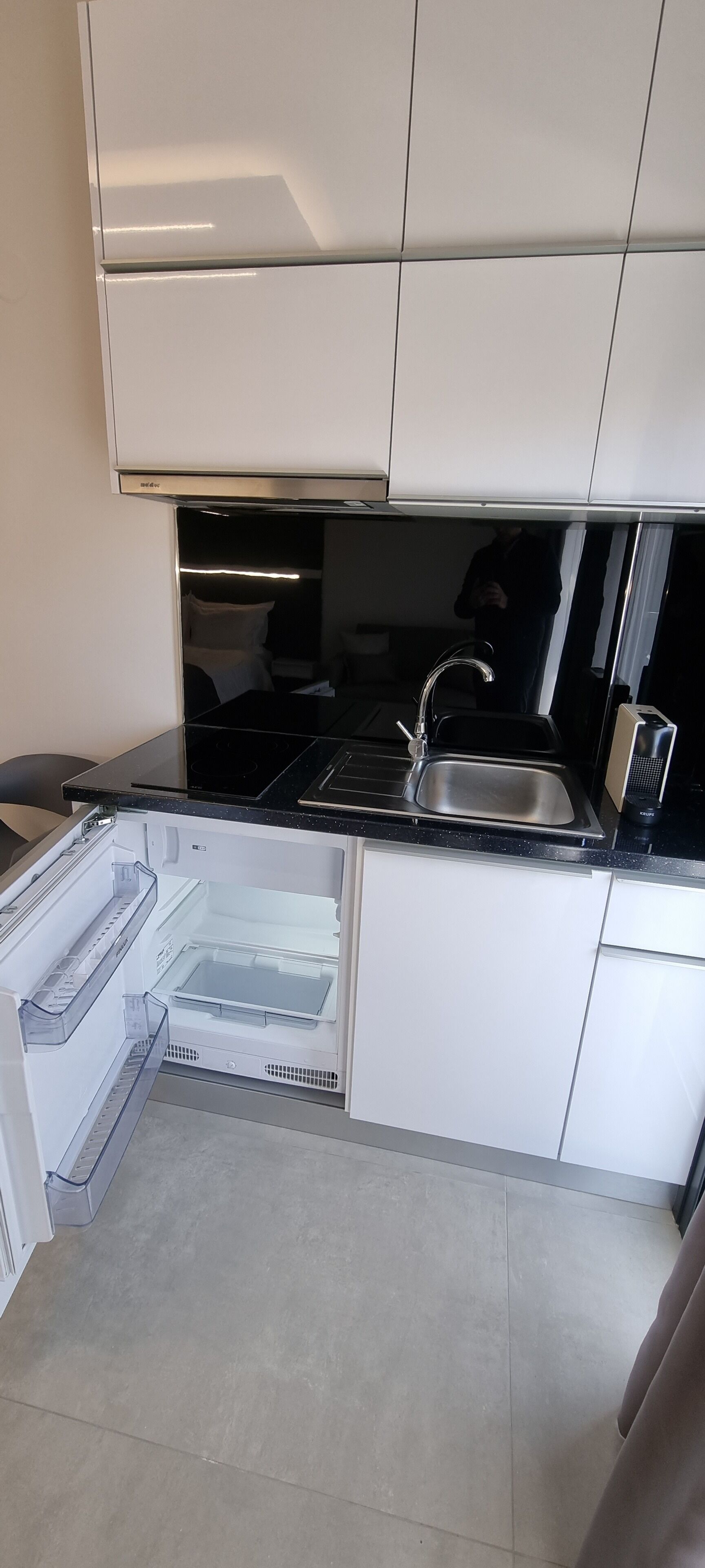 Una cocina moderna con refrigerador empotrado, pileta de acero inoxidable y encimera negra.