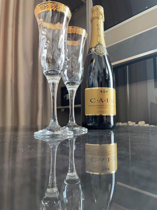 A bottle of C.A.F.I.R champagne and two glasses on a reflective surface. - LUXSUITES (Pangaio)