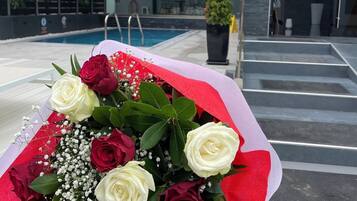 A bouquet of roses on a white chair by a poolside.