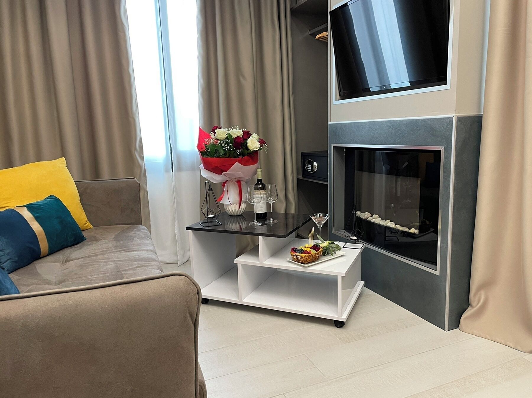 Een moderne woonkamer met een bank, een klein tafeltje met een bloemenboeket, een fles en een glas wijn.