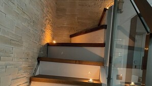 A staircase with wooden steps and a glass railing, illuminated by candles. - LUXSUITES (Pangaio)