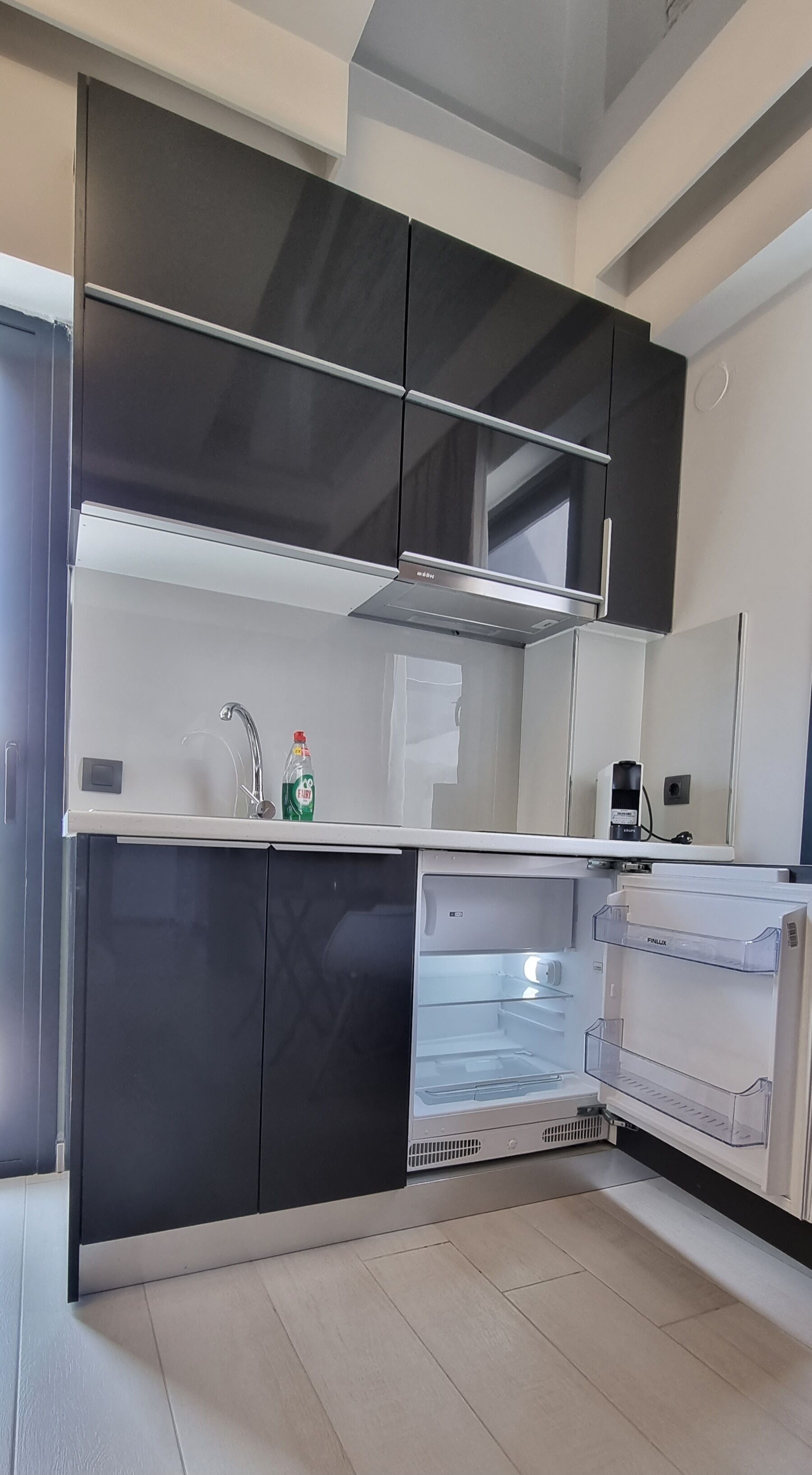 A modern kitchen with black cabinets, a white countertop, and a built-in refrigerator.