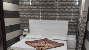 A bedroom with a bed, a nightstand, and a patterned wall. - Hotel Shri Radha Niwas (Katra)