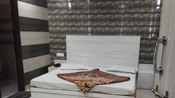 A modern bedroom with a large bed, a patterned wall, and a marble floor. - Hotel Shri Radha Niwas (Katra)