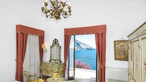 Une chambre avec un lit, une commode, un miroir et une vue sur la mer.