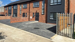 A modern two-story building with brick and dark facade, multiple windows, and a gated entrance. - New 3 Bedroom, 3 shower, ideal for Contractors,Companies & Temporary Relocation (Waltham Cross)