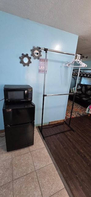 Compact room with a functional layout, featuring a refrigerator, microwave, and ample storage.