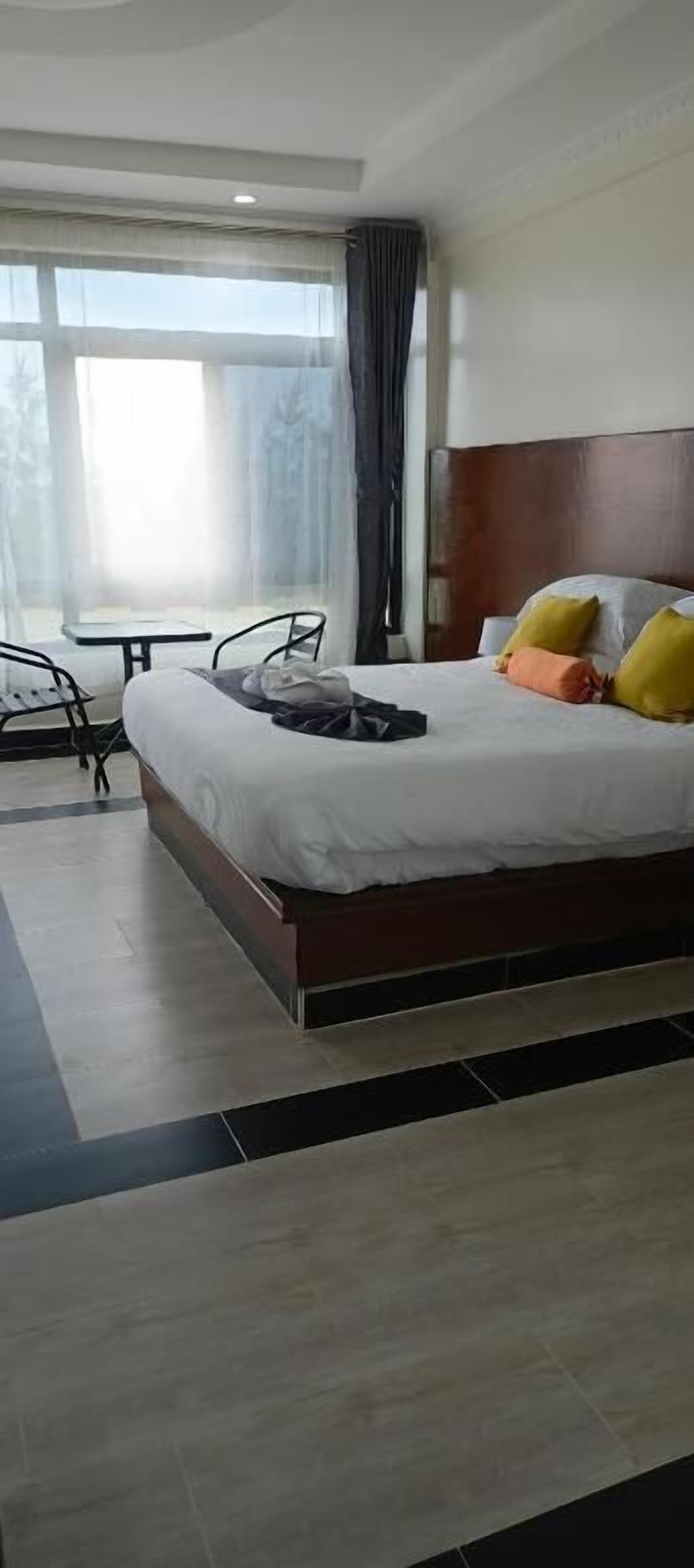 A hotel room with a large bed, a small table, and a chair.
