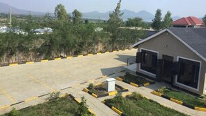 A parking lot with yellow lines, a building with large windows, and a view of distant mountains. - Key Villa (Homa Bay)