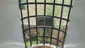 A wooden staircase leading to a glass enclosure with a view of a garden. - Key Villa (Homa Bay)