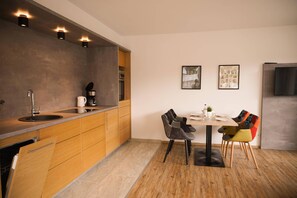 A modern kitchen with wooden cabinets, a built-in sink, and a dining area with a table and chairs.