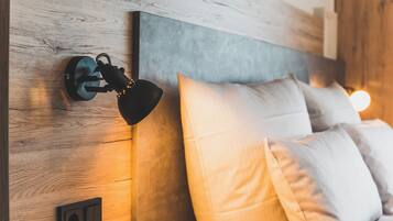 A modern bedroom with a wooden headboard, a wall-mounted lamp, and a bed with white bedding.