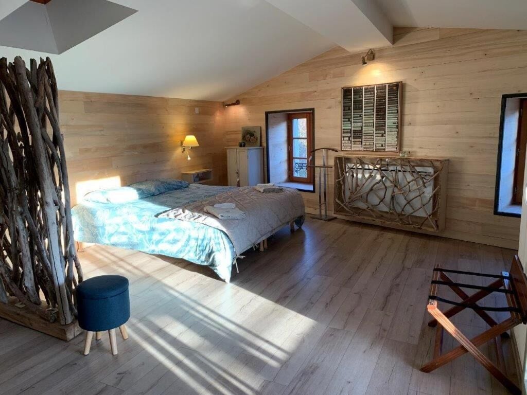 A bedroom with a bed, a window, a wooden wall, and a lamp.