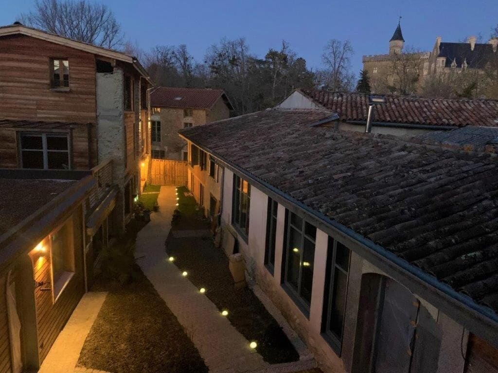 Un patio con un sendero, edificios de madera y un castillo a lo lejos.