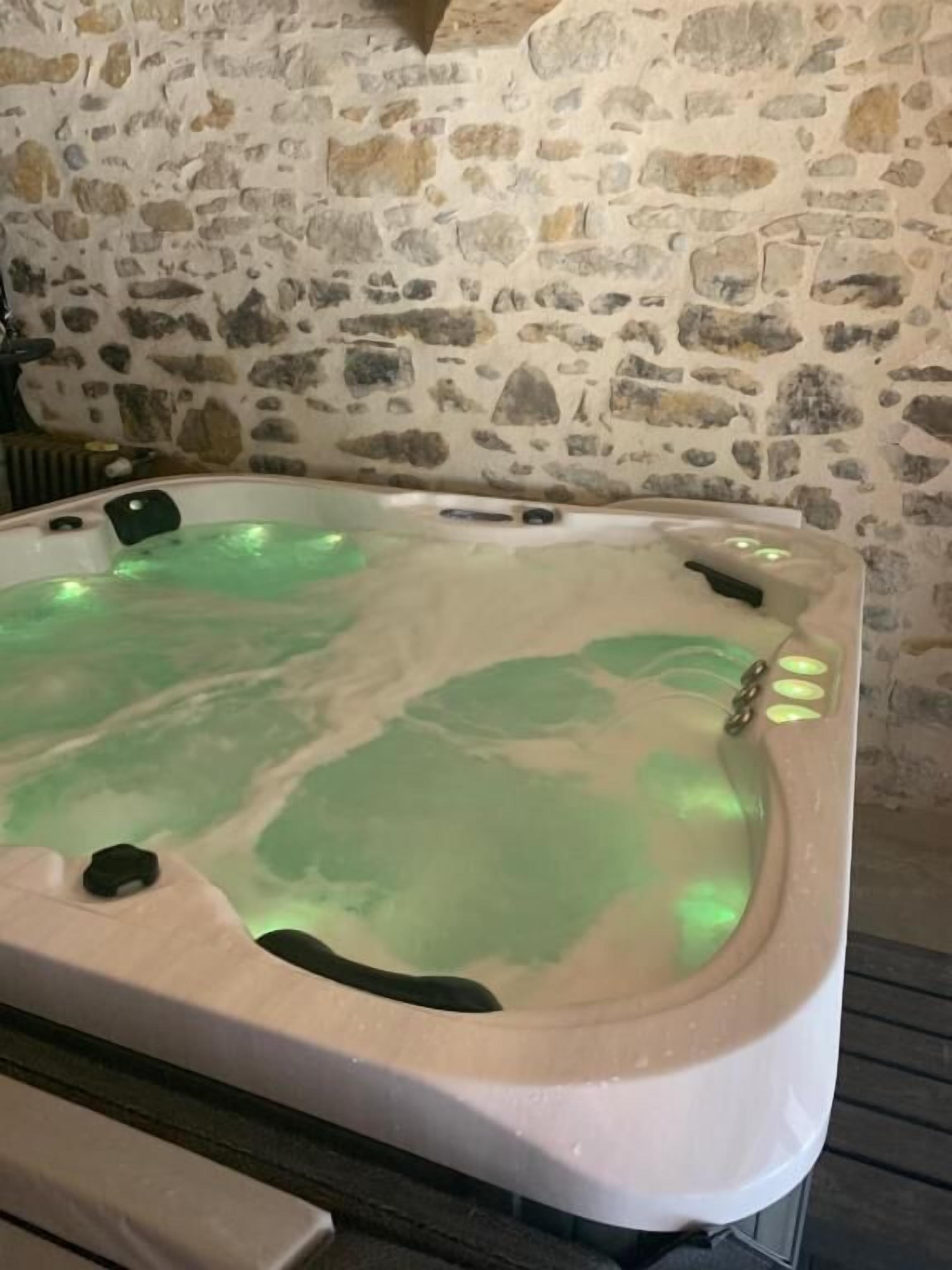 Una habitación con paredes de piedra y una bañera de hidromasaje.