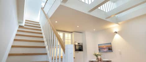 A modern interior with a staircase, a dining area, and a kitchen.