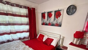 A bedroom with a bed, a bedside table, a clock, and a wall with three rose paintings. - Room-charming London Guest Room With Gar (London)