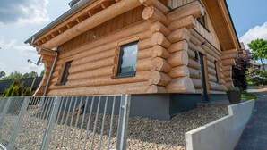 A log cabin with a sloped roof, a small window, and a metal railing in the foreground.