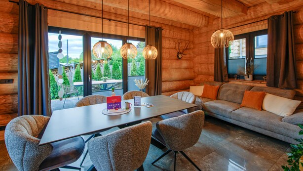 A wooden interior with a dining table, chairs, and a sofa.