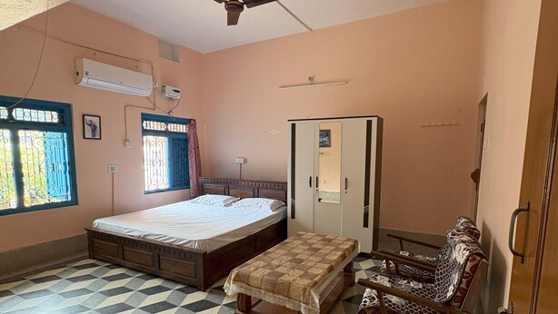 A room with a bed, a bench, a wardrobe, and a ceiling fan. - 2BHK Homestay @ Gundicha Temple Best 4 Ratha Yatra (Puri)