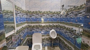 A bathroom with a toilet, sink, and bidet, all with a scenic tile backsplash. - 2BHK Homestay @ Gundicha Temple Best 4 Ratha Yatra (Puri)