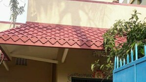 A residential building with a red-tiled roof, a blue door with a metal gate, and a parked motorcycle. - 2BHK Homestay @ Gundicha Temple Best 4 Ratha Yatra (Puri)