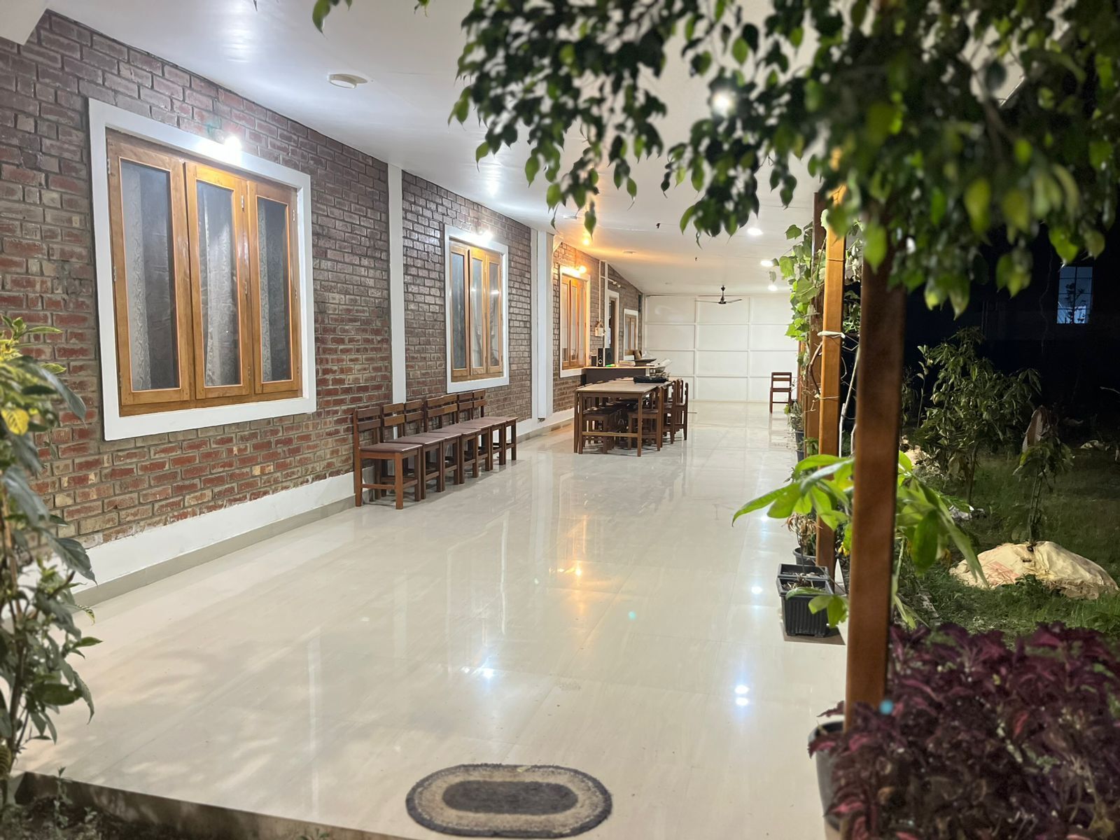 Un amplio espacio interior con piso pulido, bancos de madera, una mesa de comedor y paredes de ladrillo.