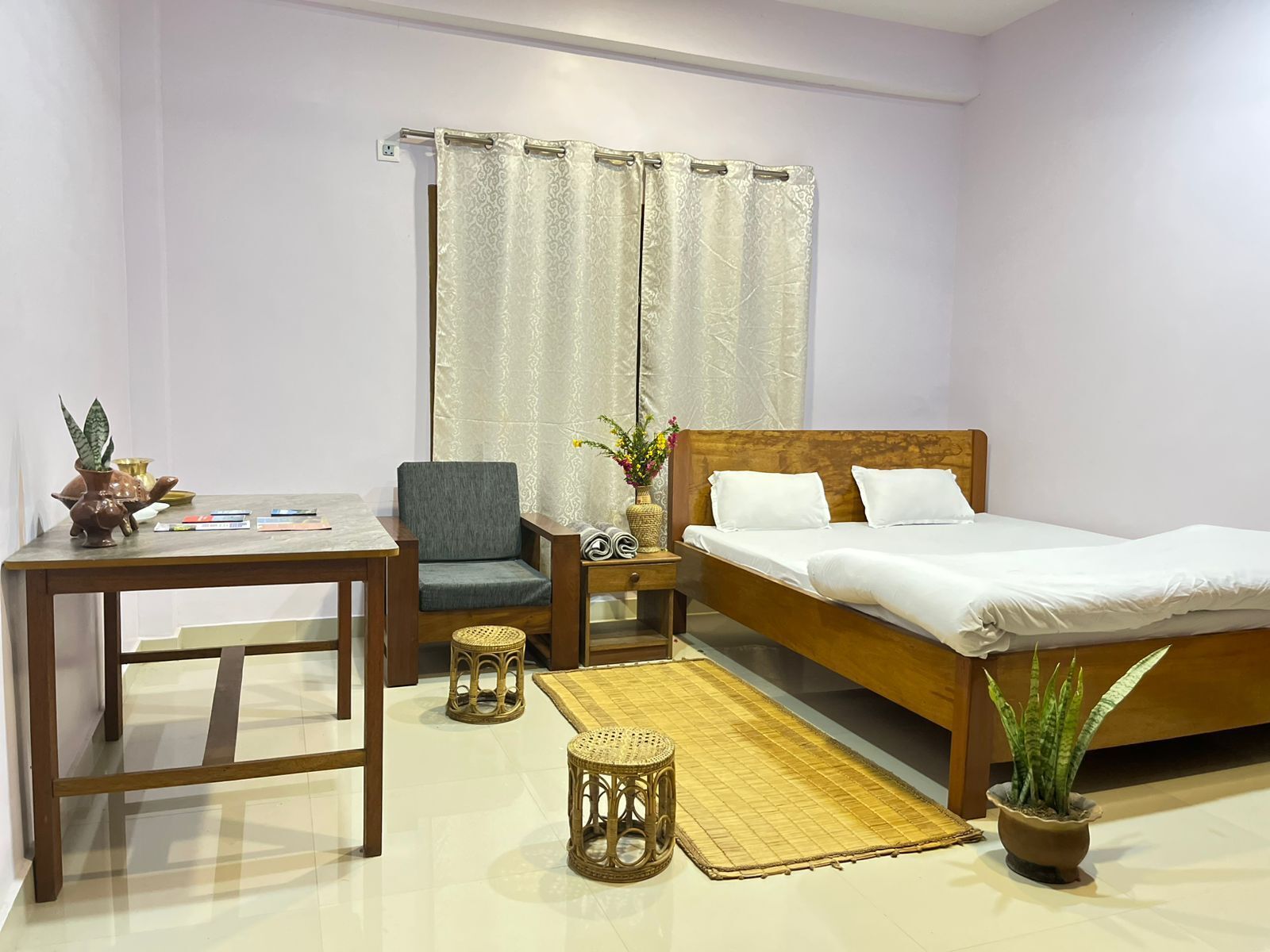 A bedroom with a bed, a chair, a table, and a small stool.