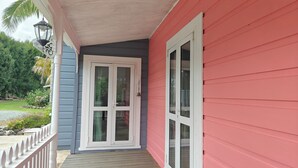 Ein Haus mit Veranda, einer weißen Tür und einer roten Außenwand.