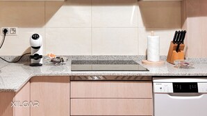 Una cocina moderna con lavavajillas integrado, tetera y bloque de cuchillos.