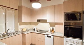 A kitchen with a dishwasher, microwave, oven, and a washing machine.