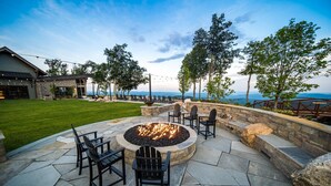 An outdoor patio with stone flooring, a fire pit, and black chairs. - 4BR Luxury Home, Hot Tub, Game Room, Walk to Pool & Grill (Boone)