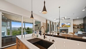 A modern kitchen with a large island, pendant lighting, and a view of the outdoors. - 4BR Luxury Home, Hot Tub, Game Room, Walk to Pool & Grill (Boone)