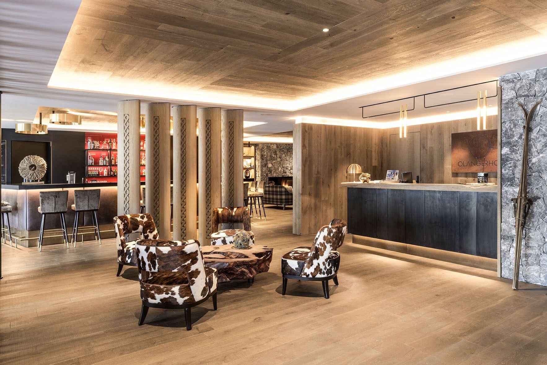 Een moderne lobby met houten vloeren, een receptiebalie en leren fauteuils.