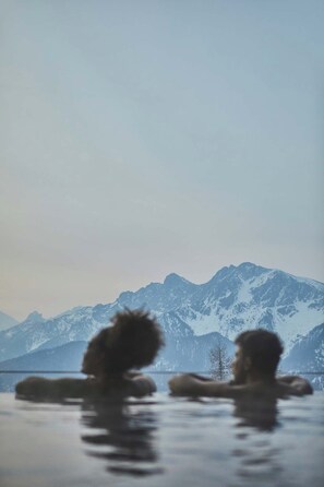 Un paysage de montagne avec des sommets enneigés et une étendue d’eau au premier plan.