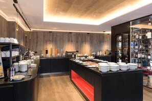 Un bar à petit-déjeuner moderne proposant une variété de plats et de boissons, un espace dédié au café et un présentoir à vin.