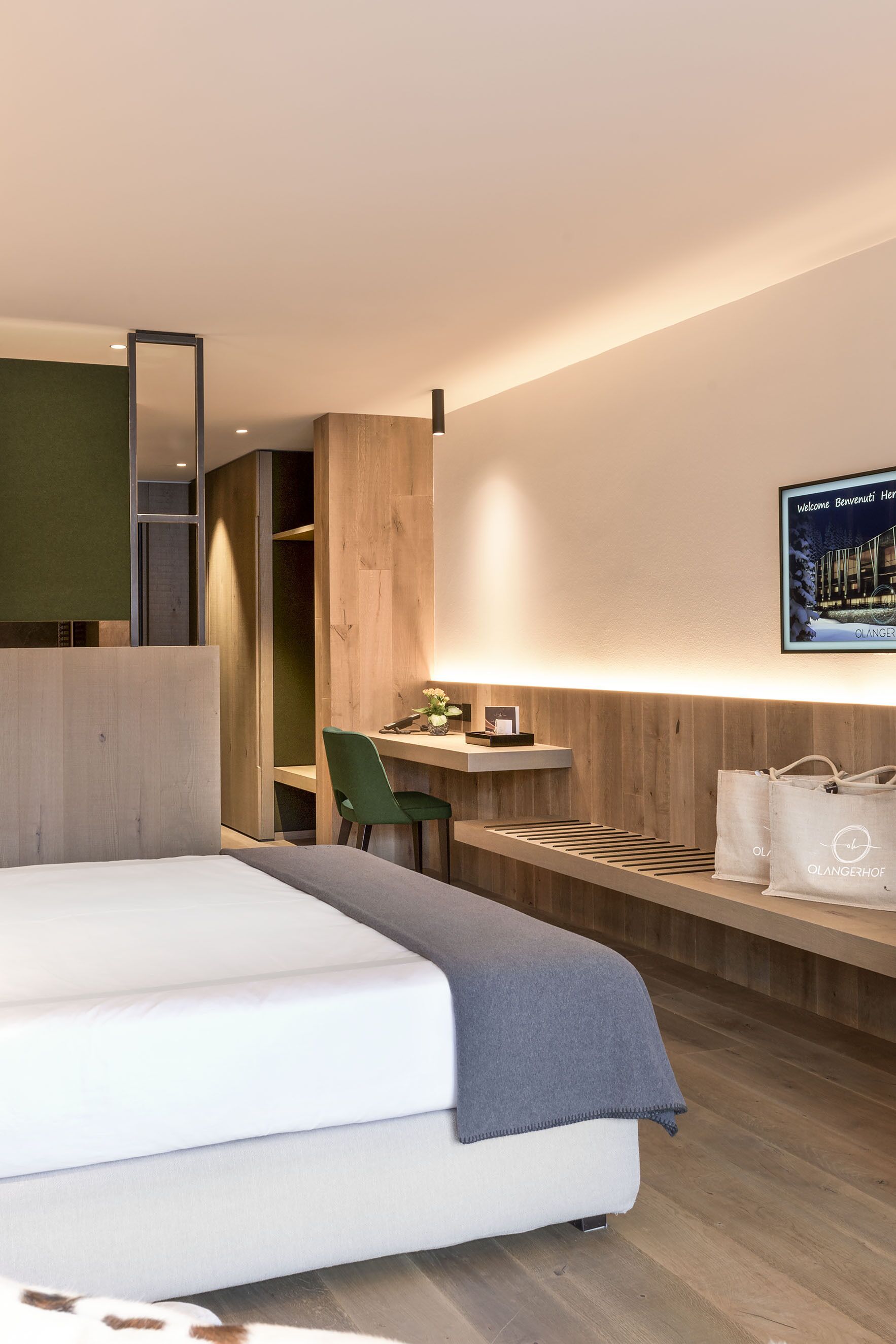 Ein modernes Hotelzimmer mit Bett, Schreibtisch, Stuhl und Spiegel, inklusive einer Willkommensanzeige.