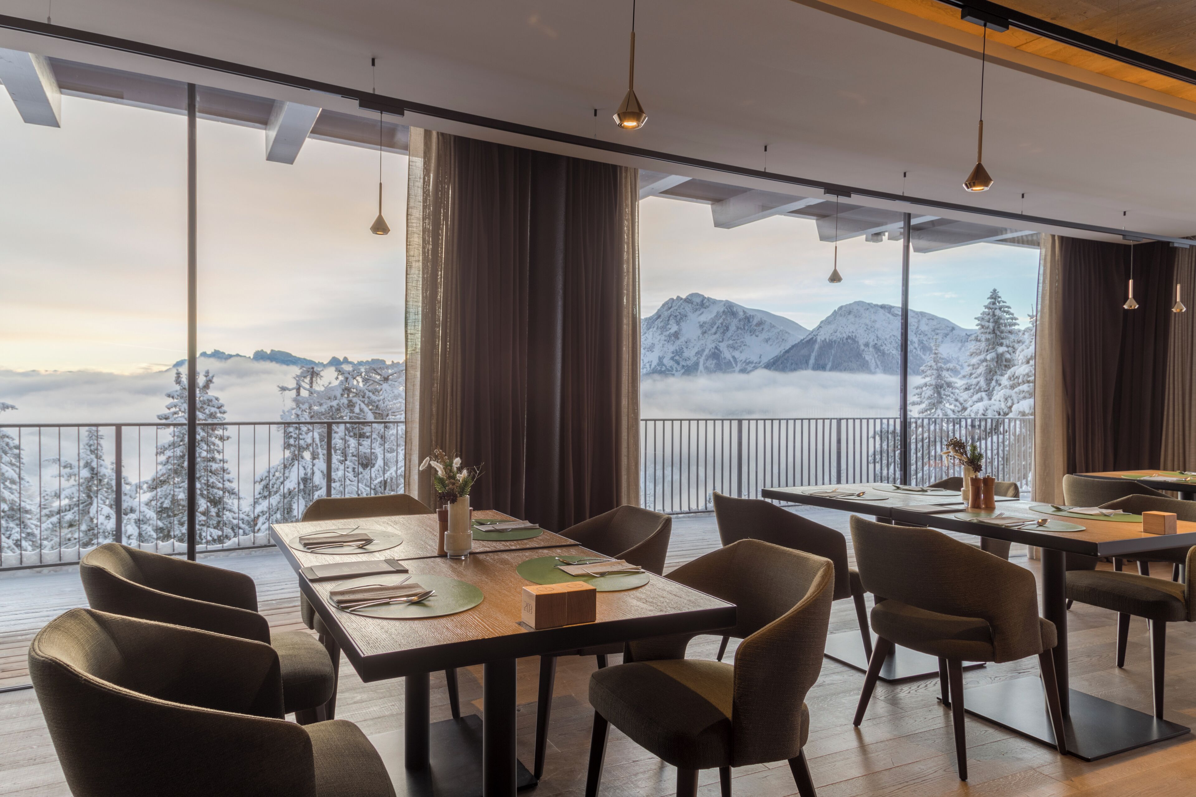 A dining area with a table set for four, large windows with a mountain view, and a balcony with a railing.