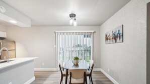 A modern kitchen with a white countertop, stainless steel sink, and a dining area with a wooden table and chairs. - The Chandler 721 I Comfy 2 bed 2 Bath (Grand Praire)