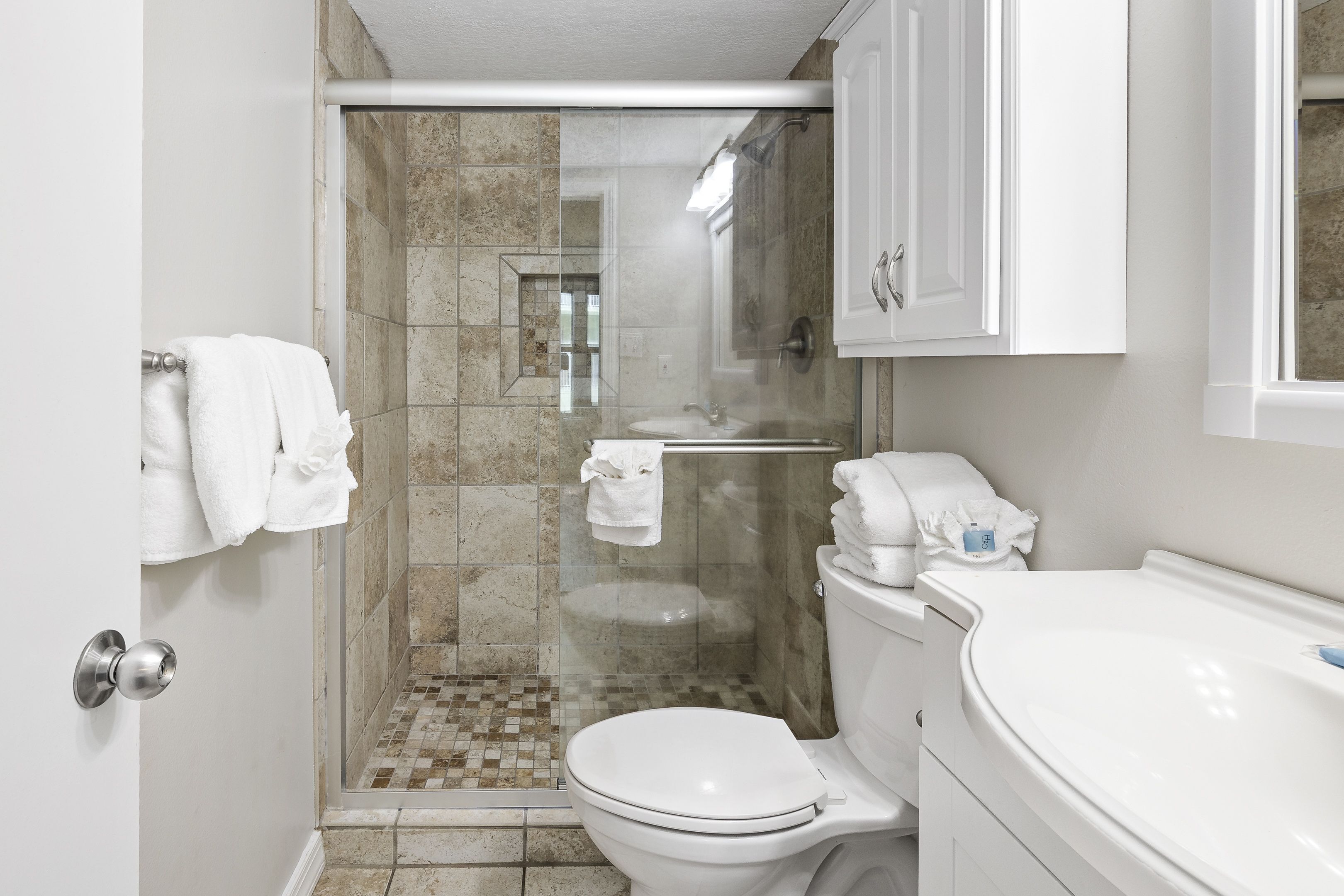 Een moderne badkamer met een douchecabine van glas, een wit toilet en een wastafelmeubel met een wastafel.