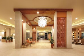A spacious lobby with a chandelier, seating areas, and potted plants.