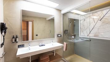 Ein modernes Badezimmer mit einem großen Spiegel, einem weißen Waschbecken, einer Duschkabine aus Glas und einem Holz-Waschtisch.
